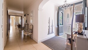 A spacious hallway with a grand chandelier, classical columns, and a large mirror reflecting the room. - Luxury Mediterranean Villa, High Standing , Sea Views (Málaga)