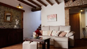 A cozy living room with a sofa, ottomans, a coffee table, and a stone wall with a mirror.
