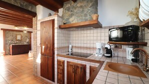 A kitchen with a stone backsplash, wooden cabinets, a built-in microwave, and a coffee maker.