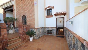A courtyard with a brick entrance, stone steps, and potted plants.