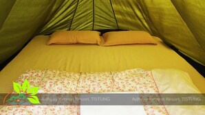 Habitación con tienda de campaña, cama, almohadas y una manta con estampado floral.