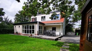 A two-story house with a patio and a small garden. - Duinweg 12 comfortable luxury holiday villa near beach (Renesse)