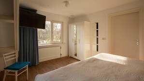 A bedroom with a bed, a chair, a wardrobe, and a window. - Duinweg 12 comfortable luxury holiday villa near beach (Renesse)