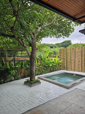 A spa area with a hot tub, surrounded by lush greenery and a bamboo fence. - Recall Isaan Isan Concept at Khaoyai (Pak Chong)