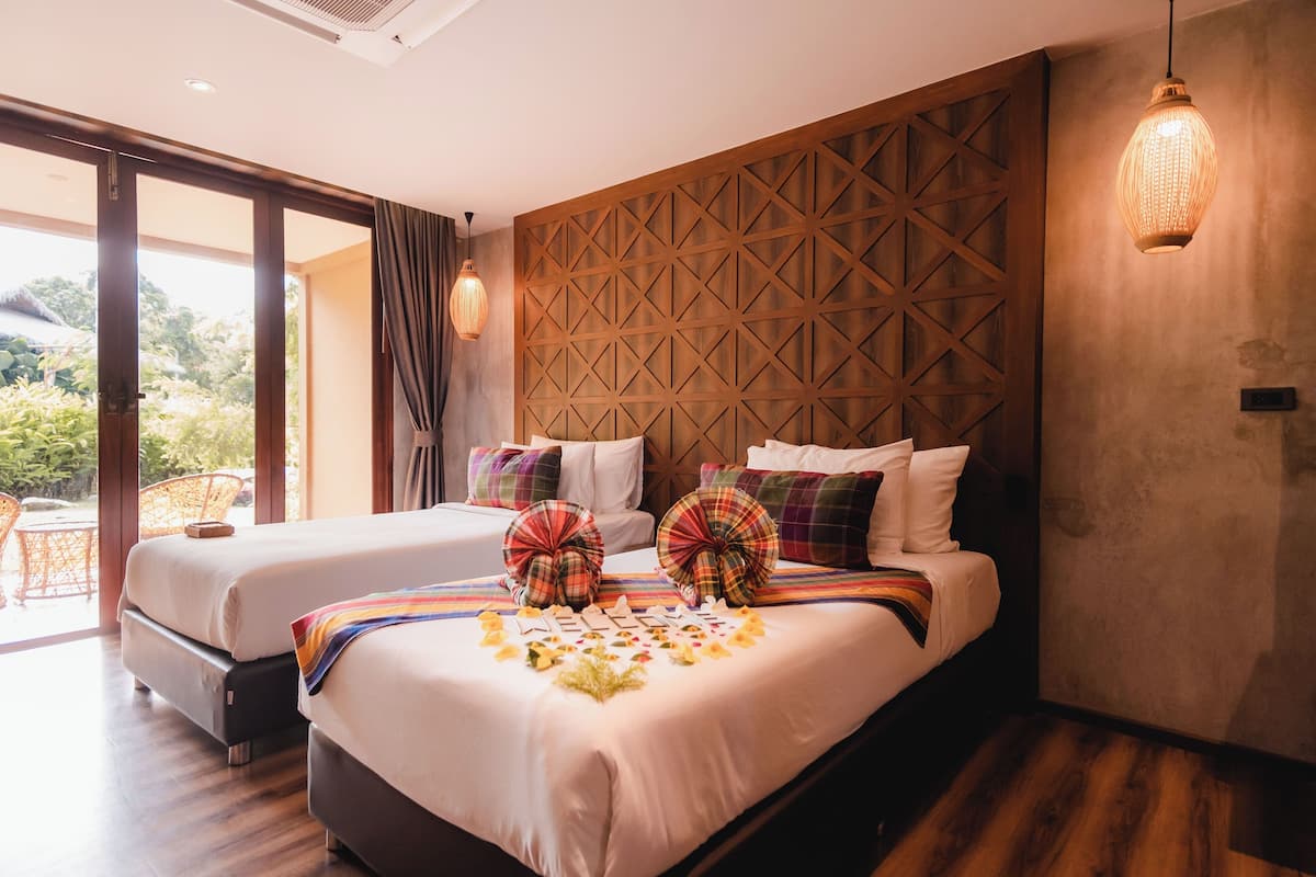 A hotel room with two beds, a wooden wall panel, and a large window.