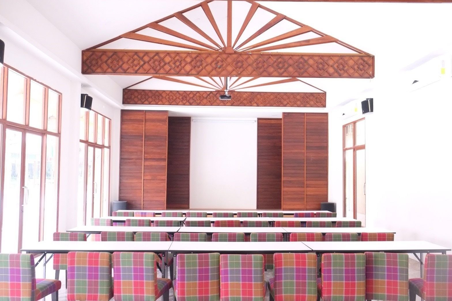 Un salón de conferencias con techo alto, paneles de madera y un escenario.