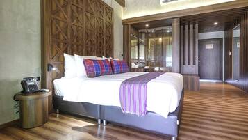Une chambre d’hôtel moderne avec un grand lit, une tête de lit en bois, un téléphone sur la table de chevet et un plancher en bois.