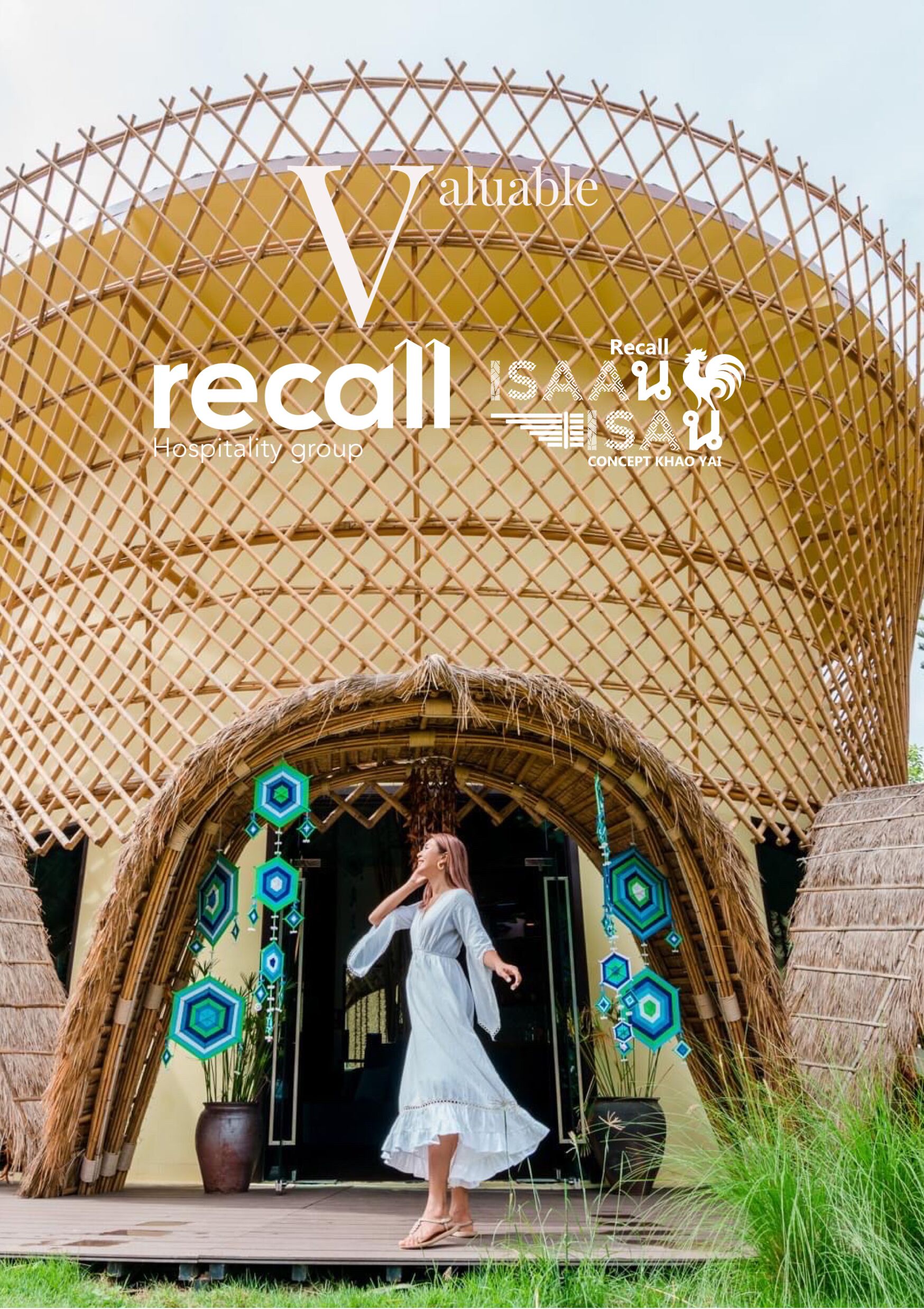 Una mujer con un vestido blanco posa frente a un edificio de techo de paja y diseños hexagonales decorativos.