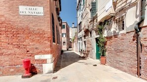 A narrow street named "Calle Del Navaro" with brick buildings, a red fire hydrant, and a potted plant. - Guggenheim Collection Venice Apartment (Venice)