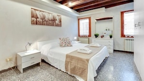 A bedroom with a bed, bedside table, lamp, and artwork on the wall. - Guggenheim Collection Venice Apartment (Venice)