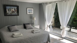 Une chambre avec un grand lit, une table de chevet avec une lampe et une vue sur la verdure.