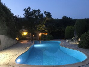 A swimming pool with a curved edge, surrounded by a stone patio and a hedge. - Gulf of Saint Tropez, French riviera villa of charm with a heated swimming pool (Le Plan-De-La-Tour)