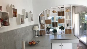 Une cuisine moderne avec des meubles blancs, un îlot central et une bibliothèque intégrée.