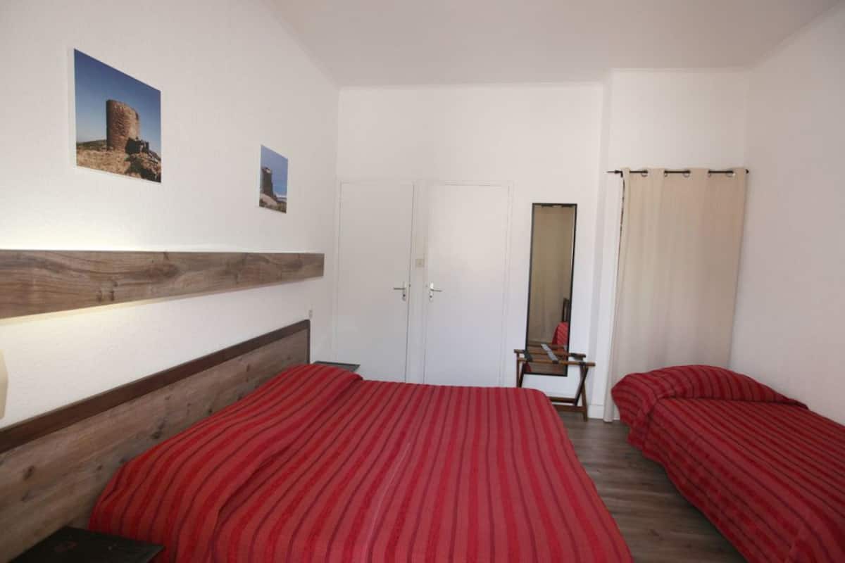 Un dormitorio con dos camas, cabecera de madera, una puerta y dos cuadros en la pared.