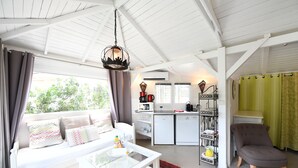 Un espacio habitable compacto con sofá, una mesa de centro de vidrio, una mesa de comedor, una zona de cocina y una silla.