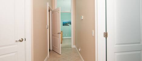Un pasillo con paredes color beige y puertas blancas, que conduce a una habitación con vista a un paisaje a través de un ventanal.
