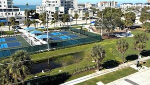 A tennis court surrounded by residential buildings and palm trees. - 4 BR Clearwater Beach Townhouse • Hot Tub • Rooftop Lounge • Beach/Gulf Views (Clearwater)
