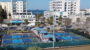 A tennis court complex with multiple courts, surrounded by residential buildings and palm trees. - 4 BR Clearwater Beach Townhouse • Hot Tub • Rooftop Lounge • Beach/Gulf Views (Clearwater)