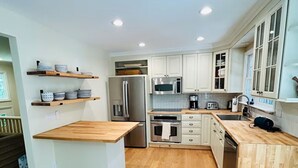 Una cucina moderna con mobili bianchi, piani di lavoro in legno ed elettrodomestici in acciaio inossidabile.