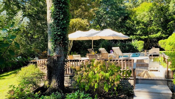 Un terrazzo in legno con posti a sedere esterni e una piscina.
