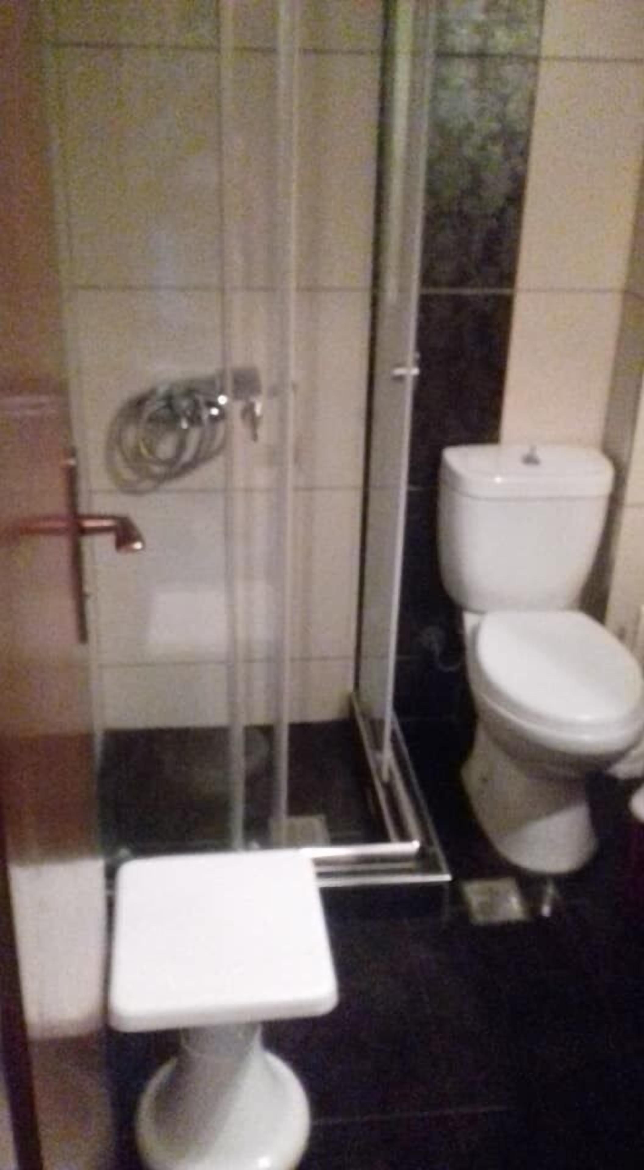 Un baño con ducha acristalada, inodoro blanco y lavamanos sobrepedal.