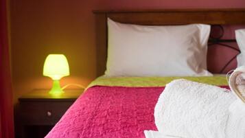 Ein Hotelzimmer mit Bett, Nachttisch mit Lampe und weißem Handtuch auf dem Bett.