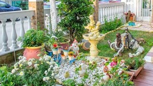 Ein gepflegter Garten mit verschiedenen Pflanzen, einer Zierbrunnen und einer Statue.