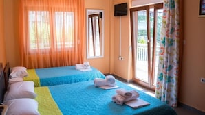 Ein Hotelzimmer mit zwei Betten, jedes mit einer blaugrünen Steudecke, und einem Balkon mit Blick.