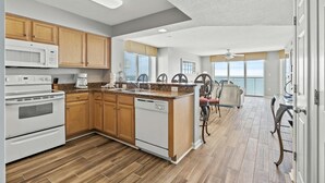 Une cuisine moderne avec des meubles en bois, des appareils électroménagers blancs et un grand îlot central.