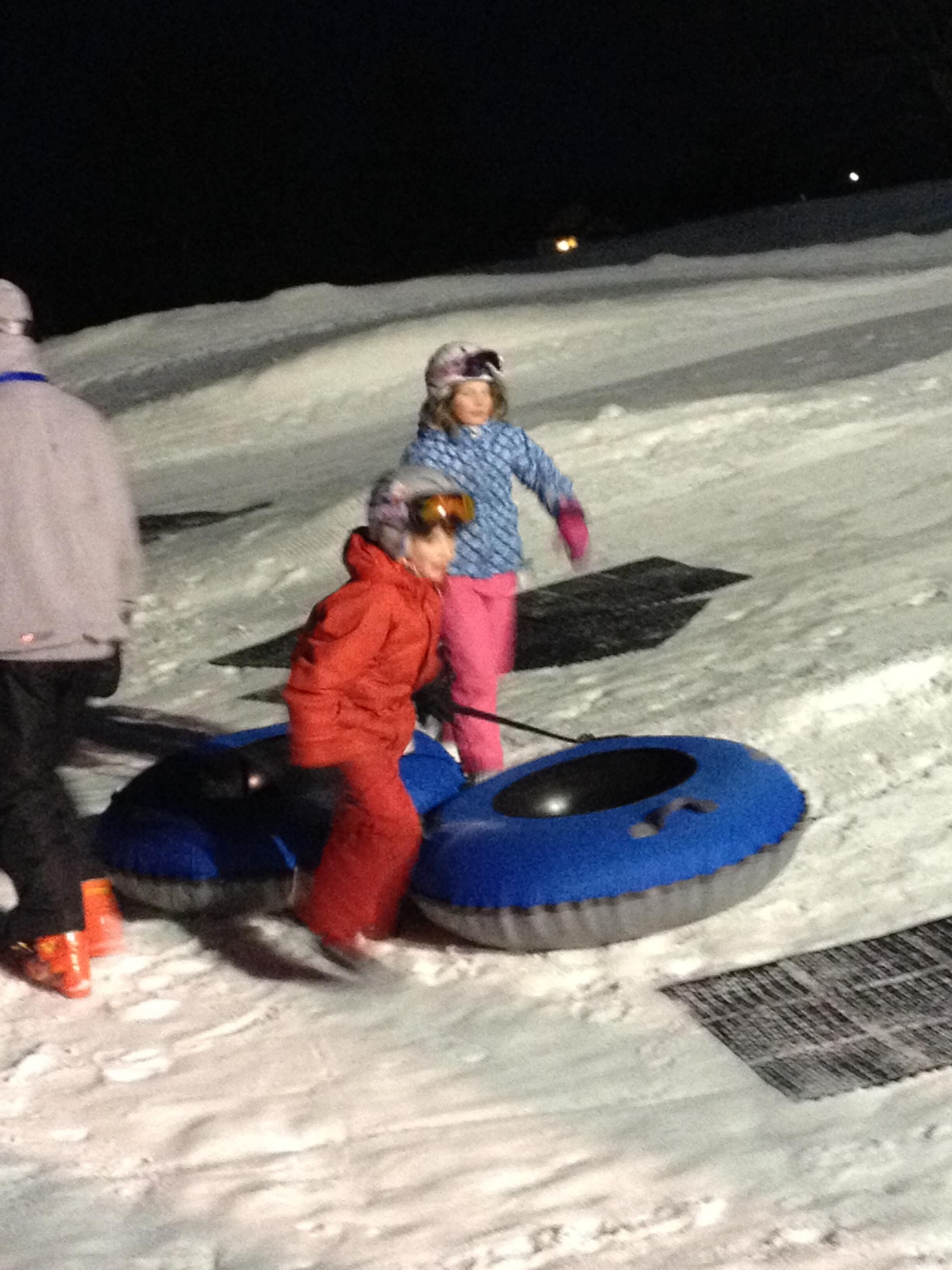 A snowy outdoor area with people using snow tubes.