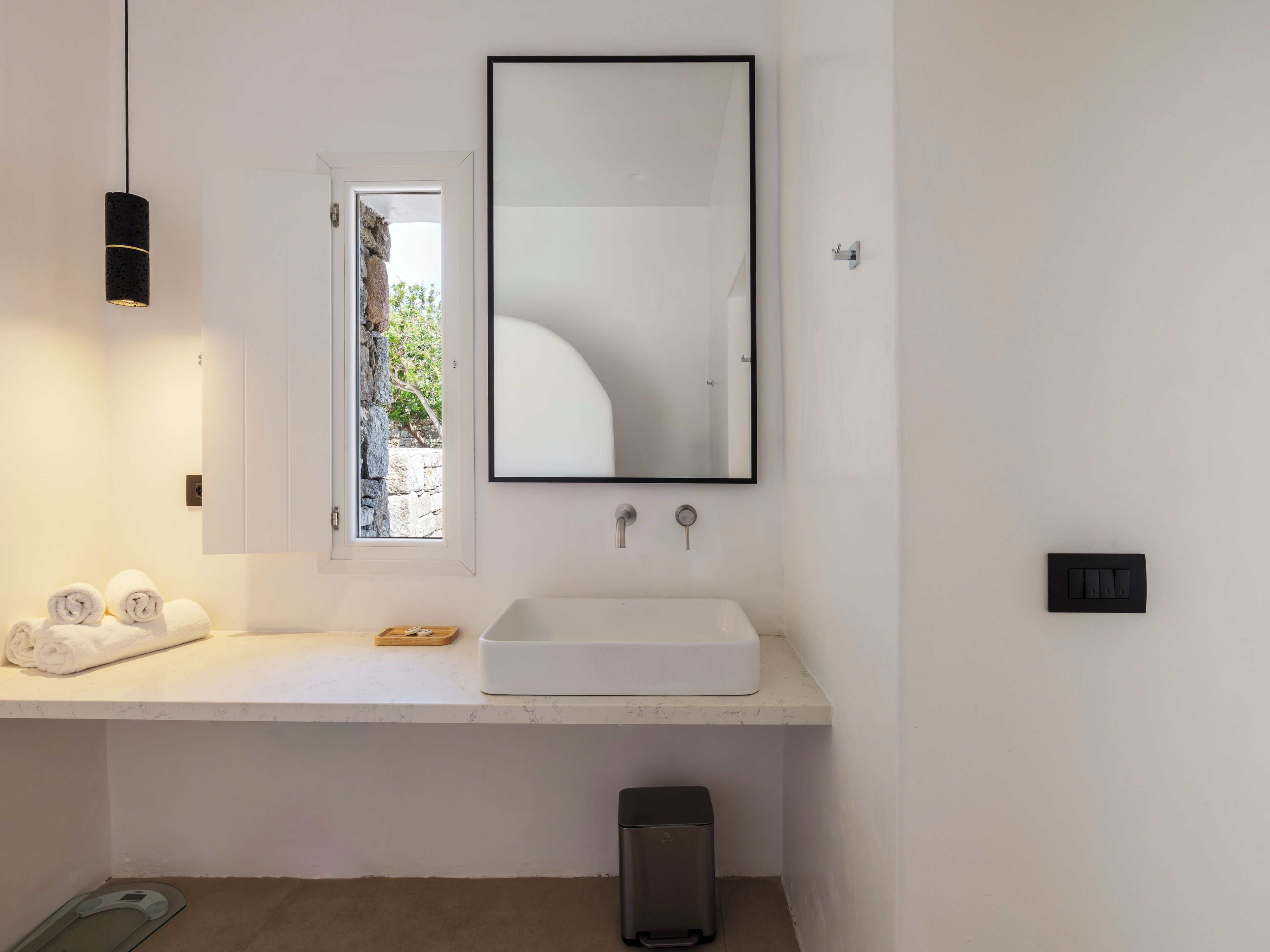 Une salle de bain moderne avec un lavabo blanc, un grand miroir et un porte-serviettes.