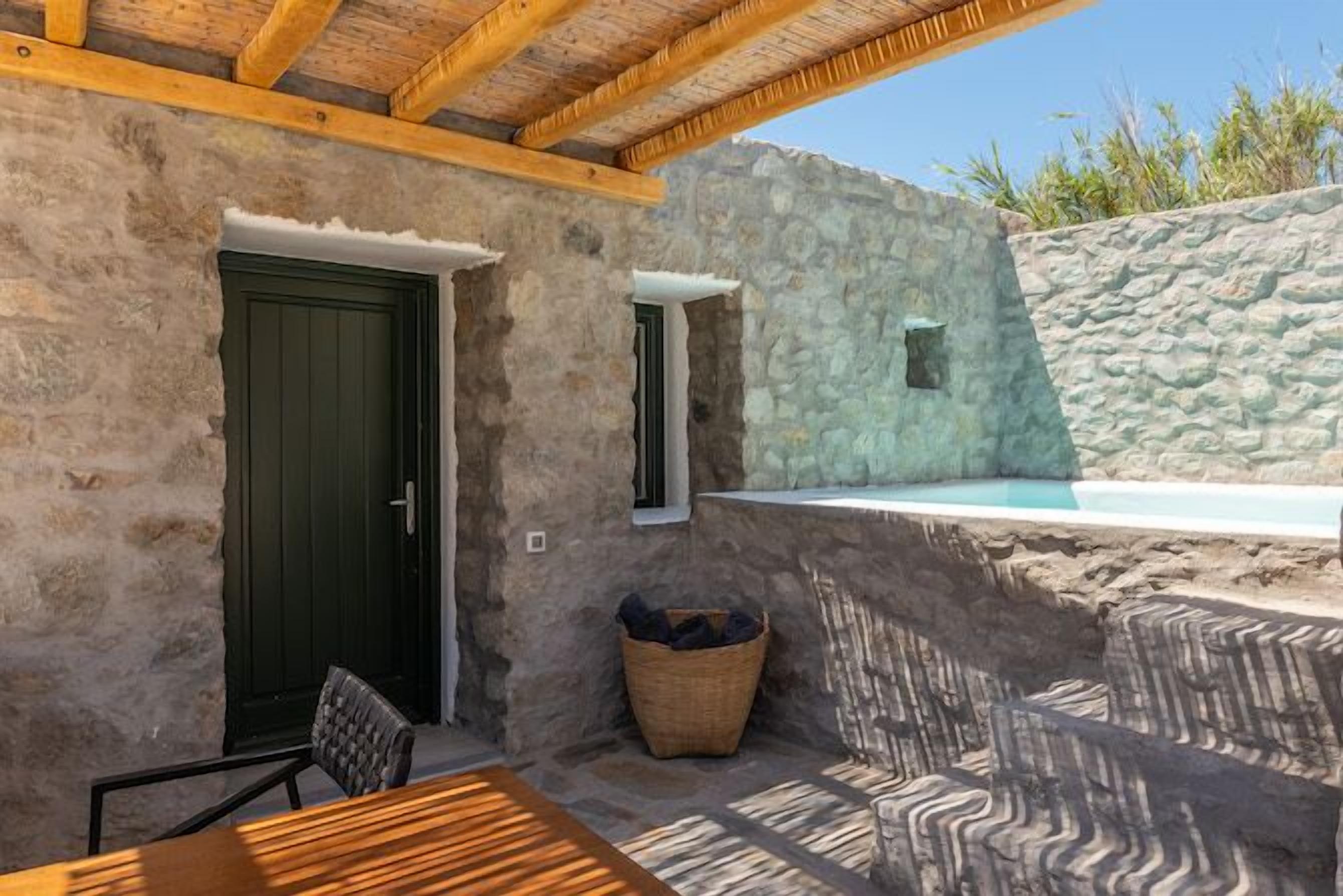 A stone exterior with a wooden door, a small window, and a stone wall.