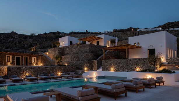 A poolside area with lounge chairs and a stone wall. - Mykonos Drops (Mykonos)