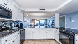 Una cocina moderna con armarios blancos, una estufa negra y suelo de baldosas.