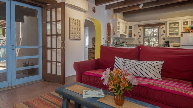Una sala de estar acogedora con un sofá rojo, una mesa de centro de madera y una puerta azul.