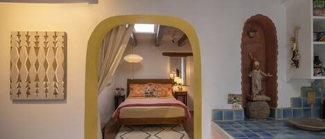 A bedroom with a bed, a nightstand, a lamp, and a decorative statue.