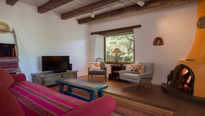 Una sala de estar acogedora con televisor, dos sillones, una mesa de centro y una chimenea.