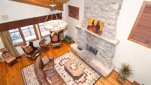 A spacious living room with a stone fireplace, leather sofas, a patterned rug, and a hanging light fixture. - Spacious 4500Sq/Ft - 5 Bed 5.5 Bath - Theater - Ski, Shop, Dine Within Steps! (Park City)