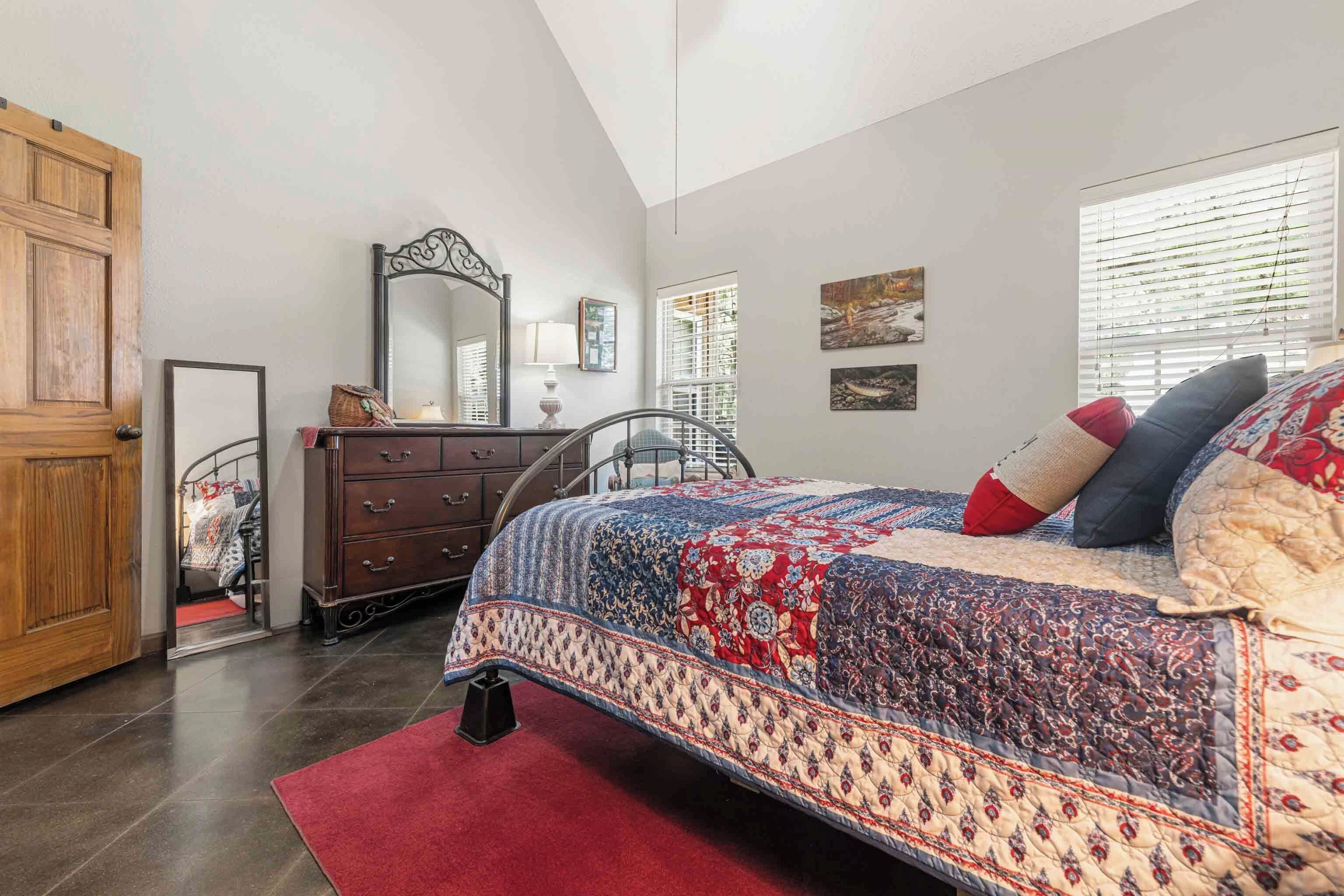 Quarto com cama grande, penteadeira, espelho e porta.
