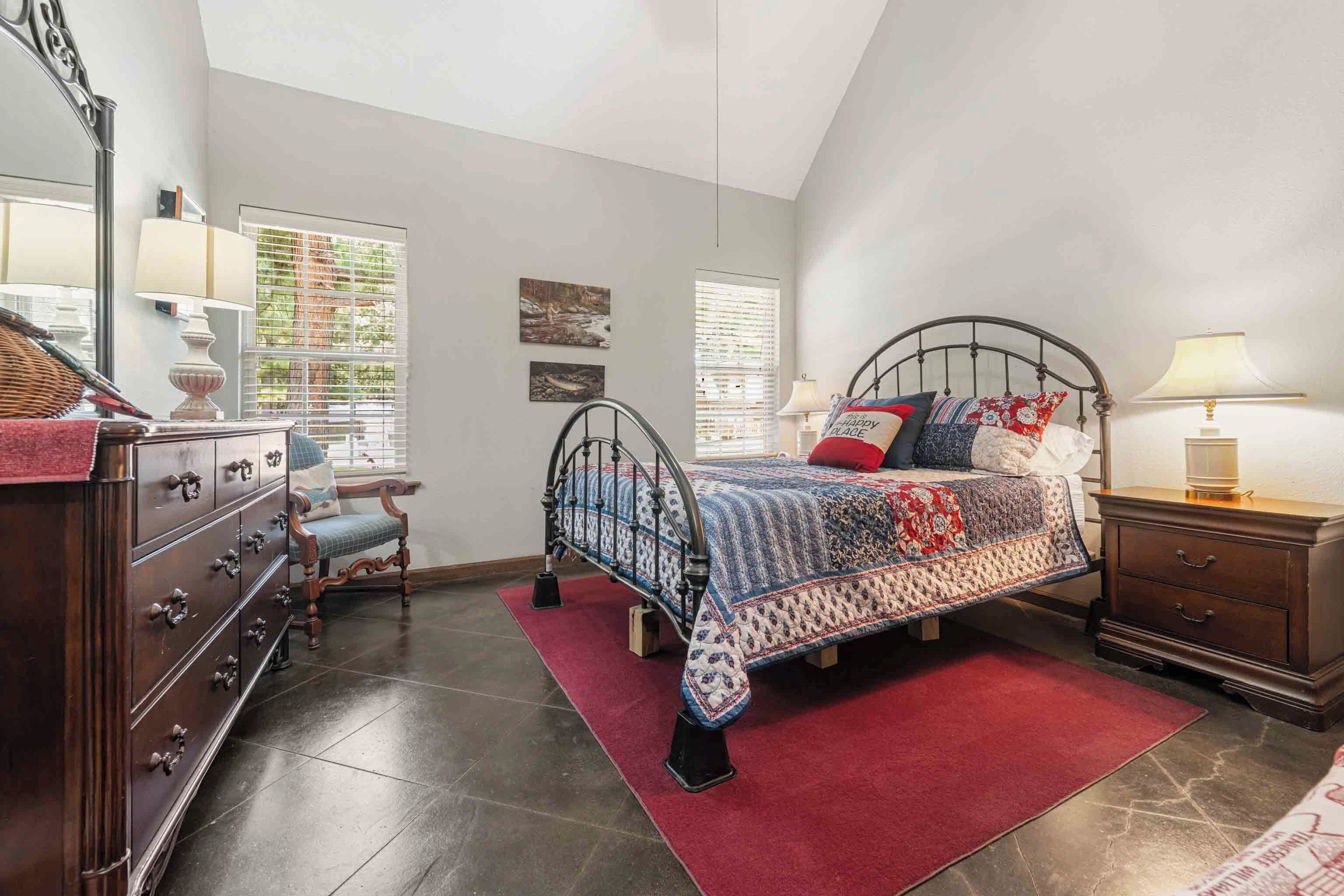 A bedroom with a bed, dresser, nightstand, and a window with blinds.