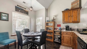 A kitchen with a dining table, chairs, wooden cabinets, and a countertop. - Your Home Base for the Little Red River, Trout Fishing & Greers Ferry Lake (Heber Springs)