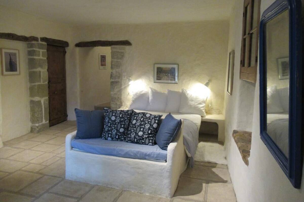 Ein gemütliches Wohnzimmer mit einem weißen Sofa, gemusterten Kissen und einer Steinwand.