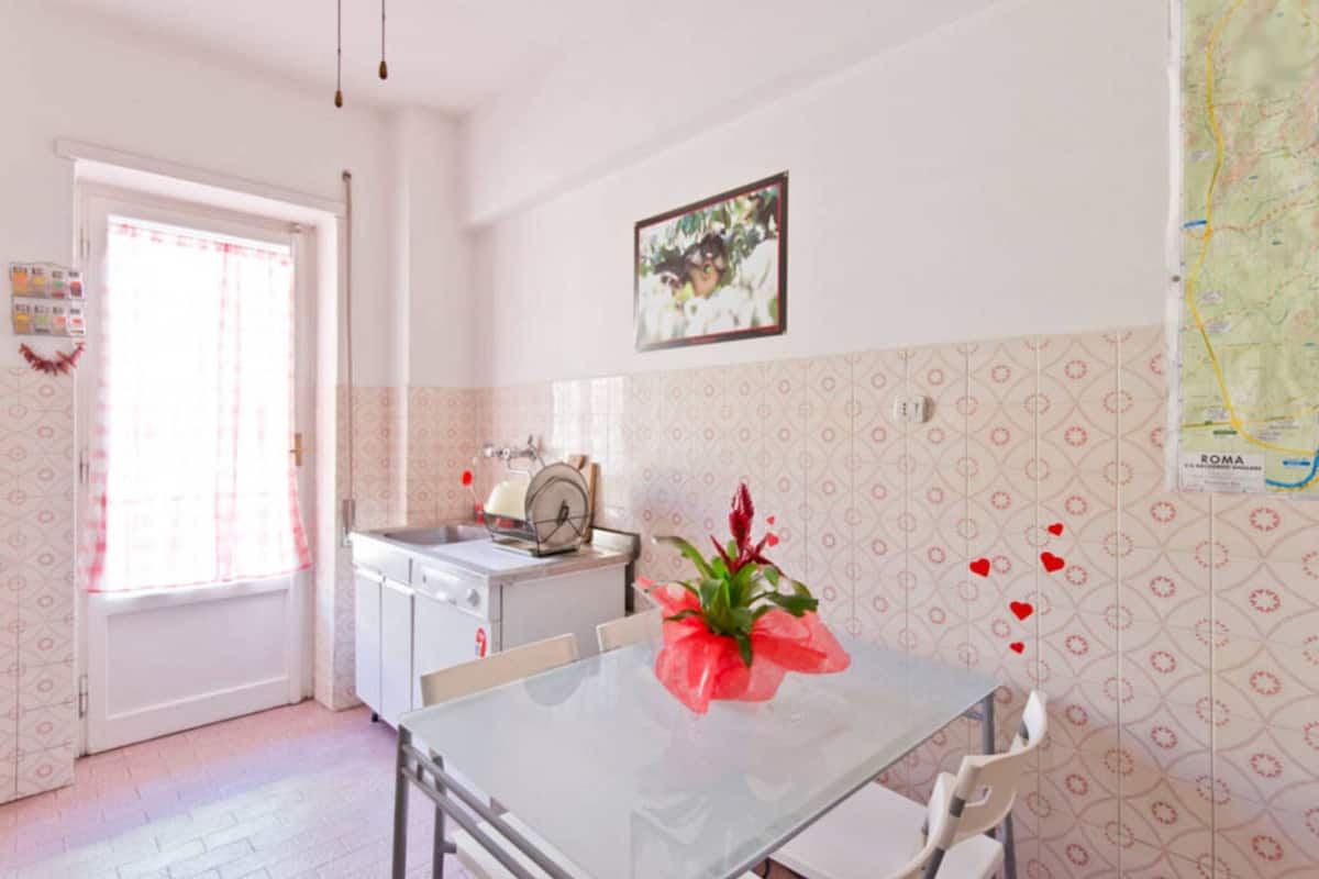 A kitchen with a white table, chairs, a sink, and a clock.