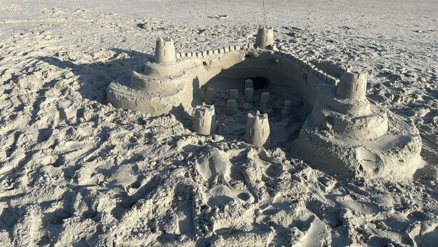 Un château de sable sur une plage, avec des vagues en arrière-plan.