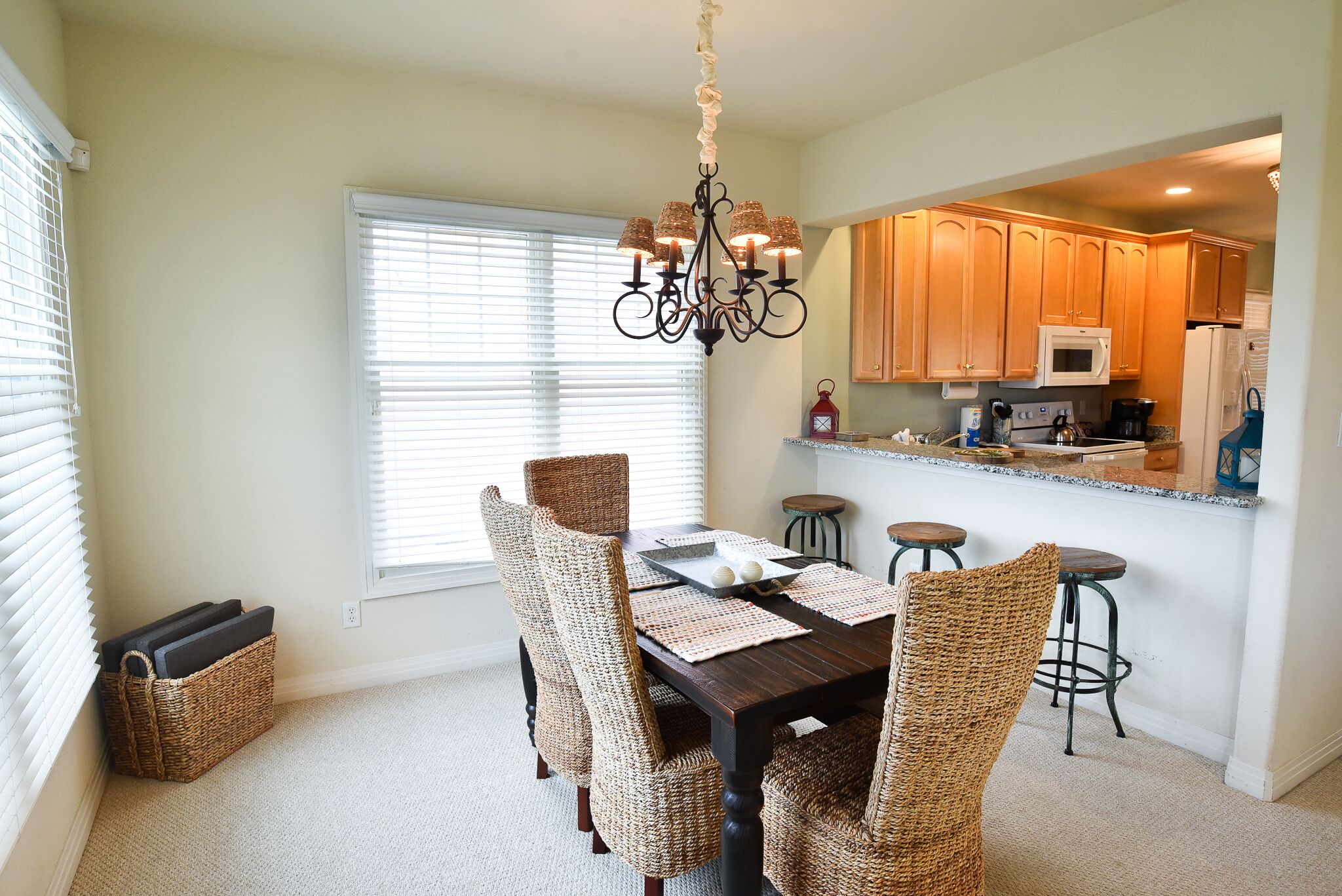 A dining area with a dark wooden table, woven chairs, and a chandelier.