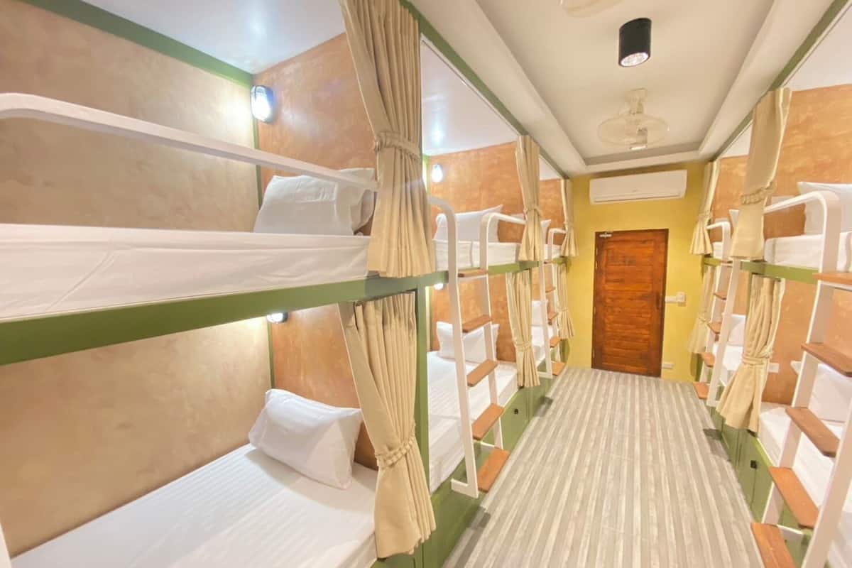 Een kamer met stapelbedden, een houten deur en een plafondventilator.