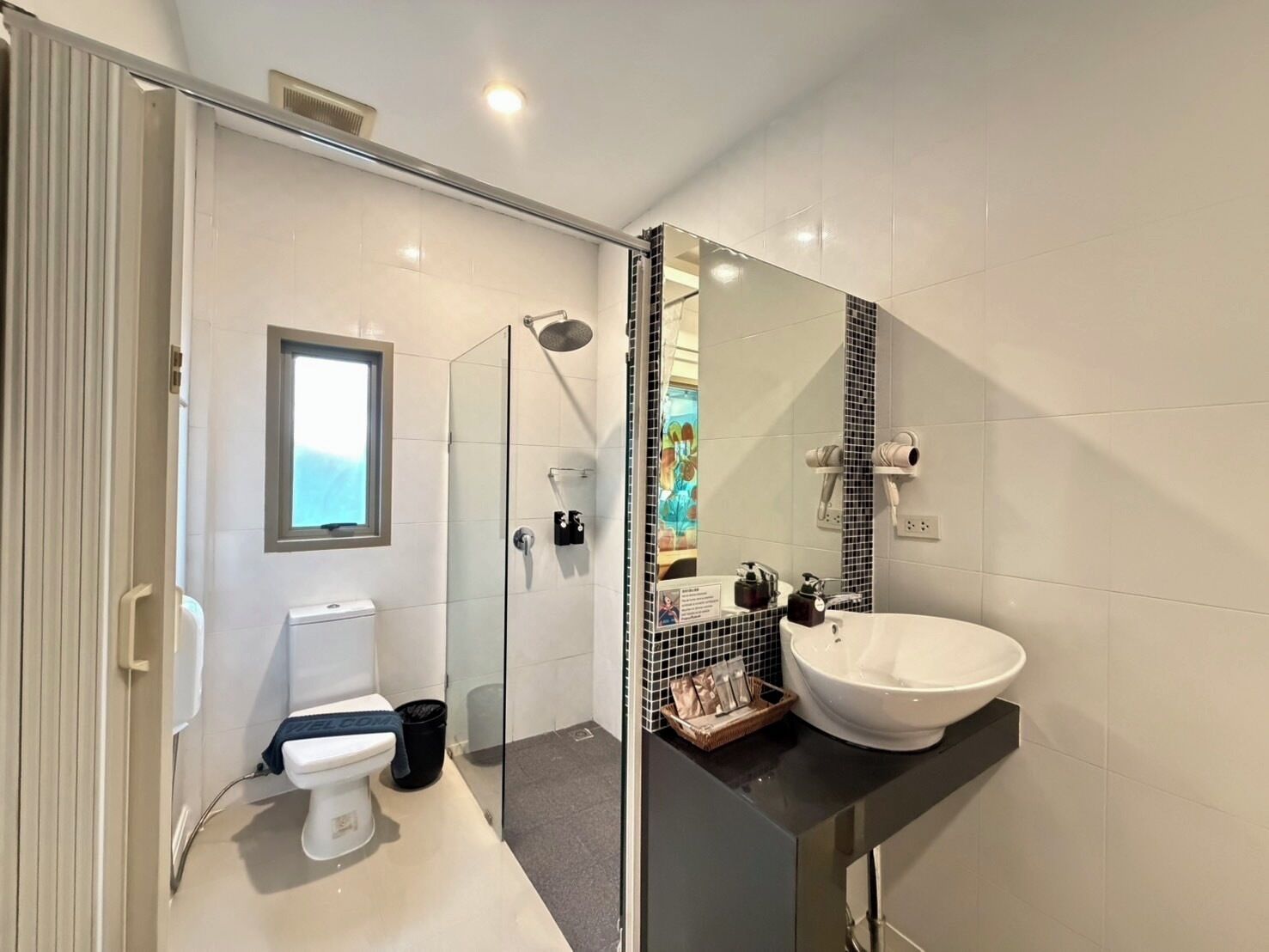 Un baño moderno con cabina de ducha de vidrio, un lavabo blanco y un espejo grande.