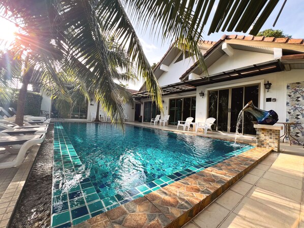 A swimming pool with clear blue water, surrounded by white lounge chairs and a tiled deck. - The Snug Airportel (Sa Khu)