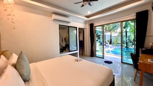 Een slaapkamer met een bed, een plafondventilator, een airconditioningapparaat, een bureau en uitzicht op een buitenzwembad.