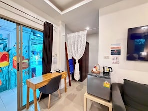 A compact living space with a kitchenette, a dining area, and a seating area with a sofa. - The Snug Airportel (Sa Khu)